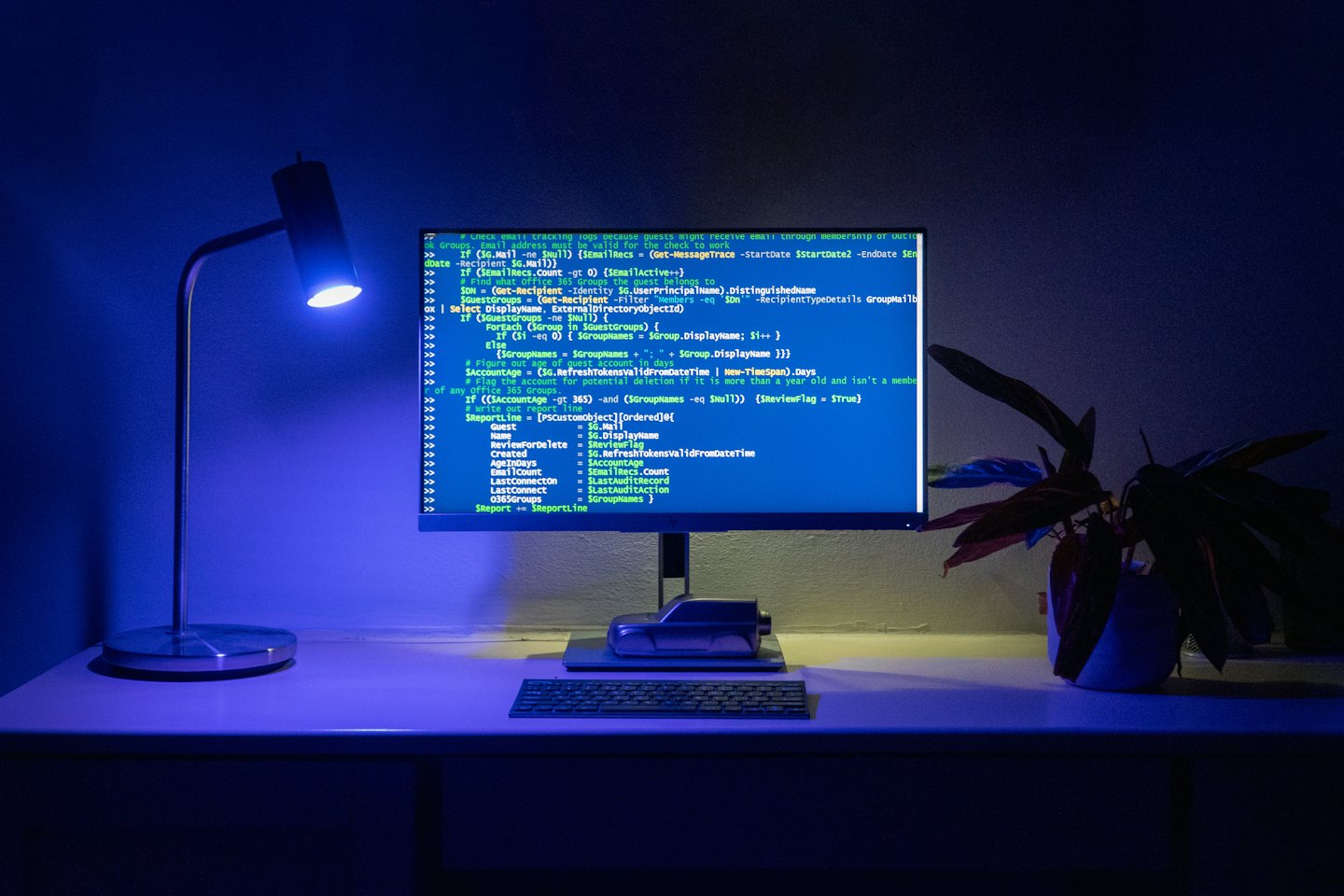 Monitor de computadora mostrando código en un escritorio con una lámpara.