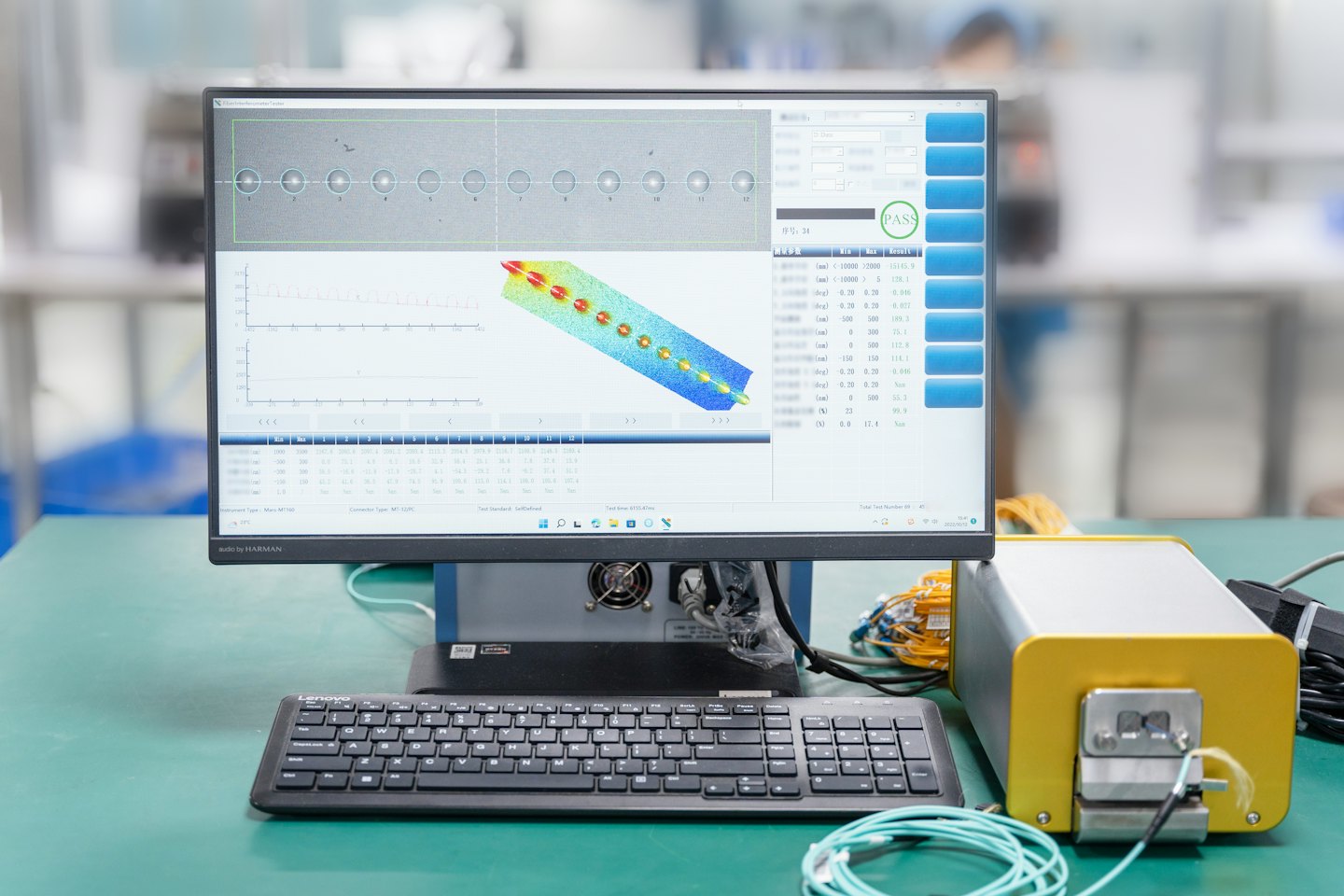 Un monitor de computadora muestra gráficos técnicos conectados a maquinaria industrial en un banco de trabajo.